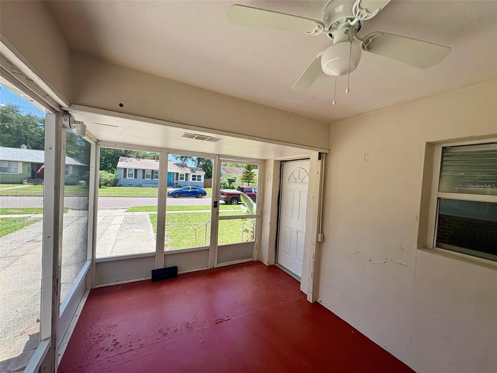 A screened-in porch with a red floor, ceiling fan, and views of a residential street — 3455 7TH AVENUE N, ST PETERSBURG, FL