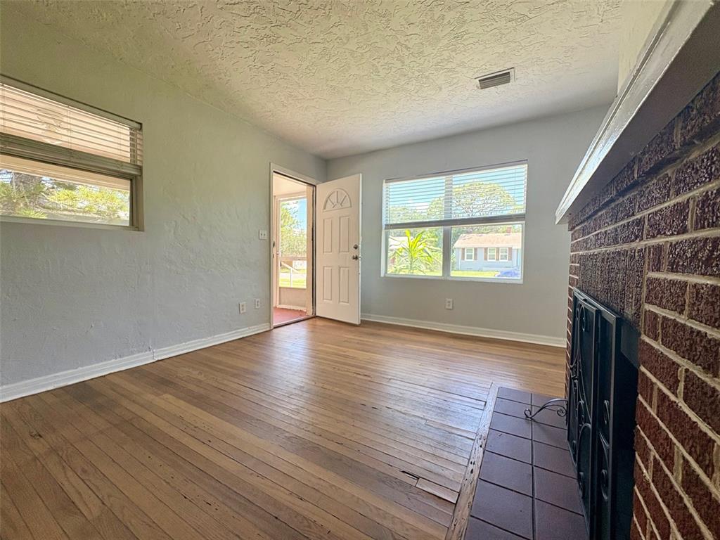 A living room with hardwood floors, a brick fireplace, and a white front door — 3455 7TH AVENUE N, ST PETERSBURG, FL