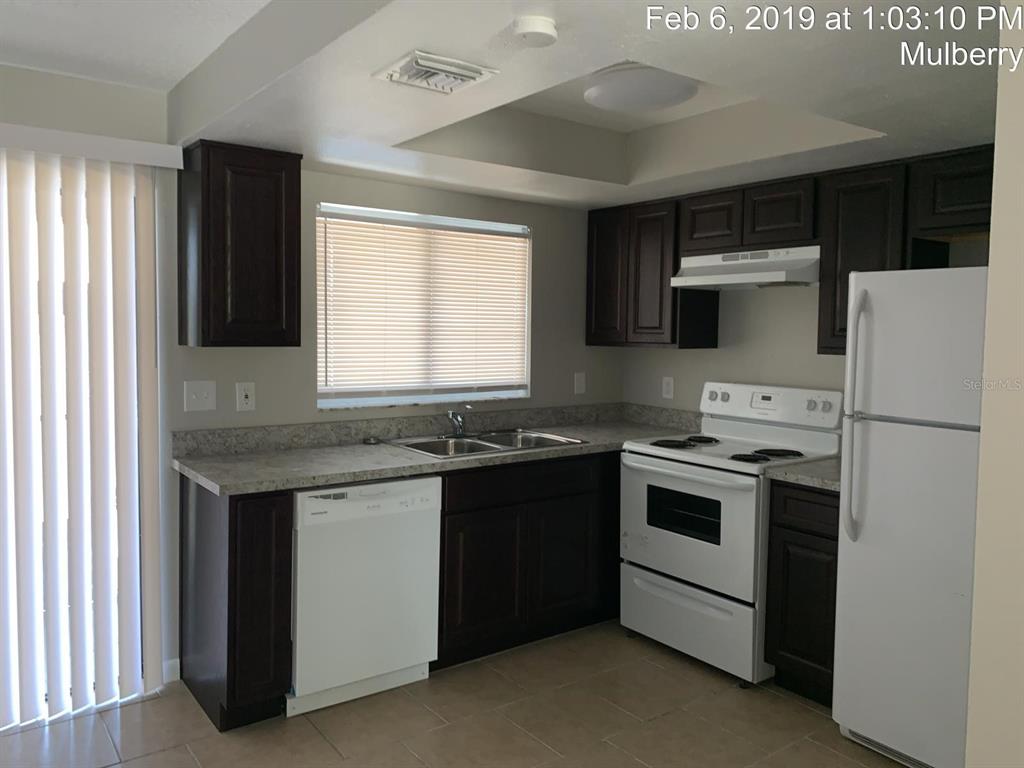 A kitchen features dark wood cabinets, white appliances, and light-colored countertops — 181 DIESEL ROAD, MULBERRY, FL