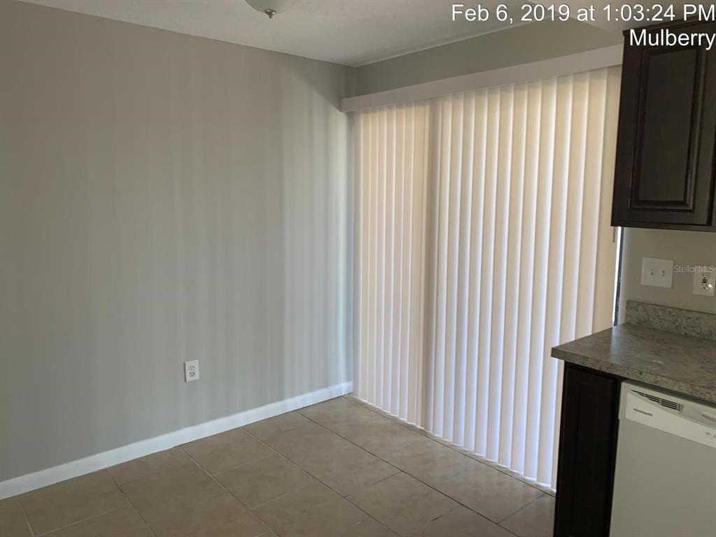 A dining area features light-colored tile flooring, gray walls, and a sliding glass door — 181 DIESEL ROAD, MULBERRY, FL