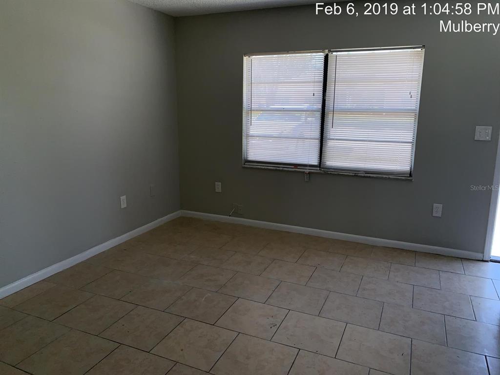 An empty room features light-colored tile flooring, gray walls, and a window with blinds — 181 DIESEL ROAD, MULBERRY, FL