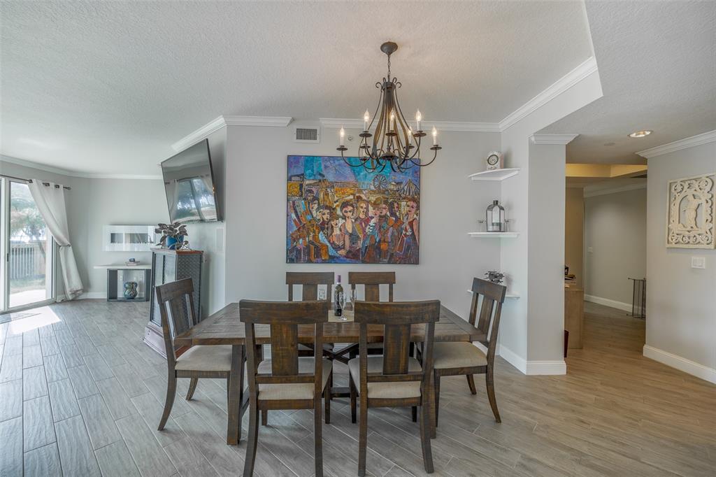 A dining room features a wooden table, six chairs, a chandelier, and colorful wall art — 555 5TH AVENUE NE UNIT 183, ST PETERSBURG, FL