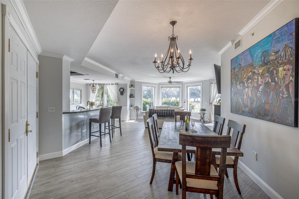 An open-concept dining area and living room with gray tile floors and a large chandelier — 555 5TH AVENUE NE UNIT 183, ST PETERSBURG, FL