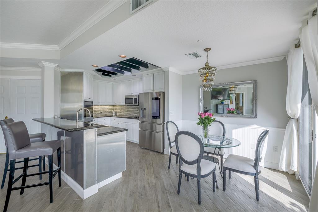 A kitchen and dining area with stainless steel appliances, white cabinets, and a glass table — 555 5TH AVENUE NE UNIT 183, ST PETERSBURG, FL