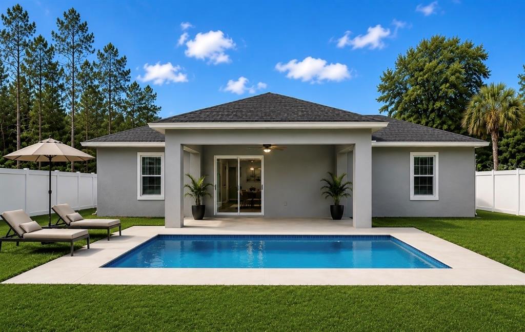 A backyard features a swimming pool, a covered patio, and two lounge chairs on grass — 18 FLAMINGO DRIVE, PALM COAST, FL