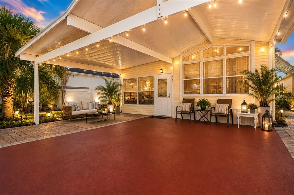 A covered patio with a red concrete floor, outdoor seating, and string lights at dusk — 429 CITRUS RIDGE DRIVE, DAVENPORT, FL