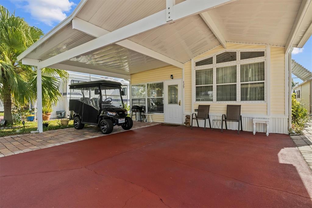 A yellow mobile home features a covered carport, a red concrete driveway, and a golf cart — 429 CITRUS RIDGE DRIVE, DAVENPORT, FL