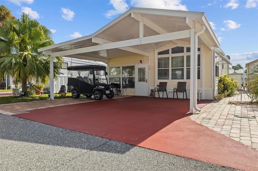 A yellow manufactured home features a covered carport with a golf cart and paved driveway — 429 CITRUS RIDGE DRIVE, DAVENPORT, FL