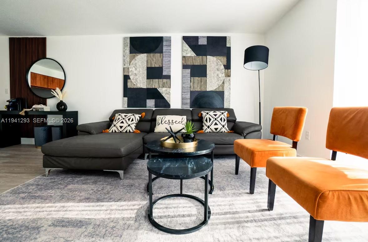 A living room features a grey sectional sofa, two orange chairs, and a nesting coffee table — 1200 Brickell Bay Dr # 3524, Miami FL 33131, MIAMI, FL