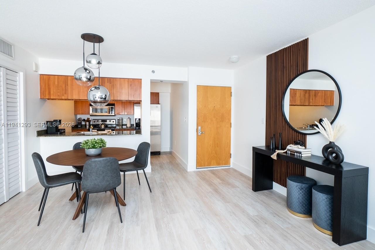 A dining area features a round table, modern pendant lights, and a wood-slatted accent wall — 1200 Brickell Bay Dr # 3524, Miami FL 33131, MIAMI, FL