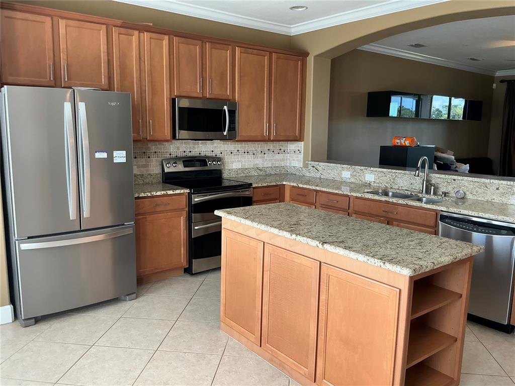 A kitchen features wood cabinets, granite countertops, stainless steel appliances, and a central island — 7059 ISLAMORADA CIRCLE, SEMINOLE, FL