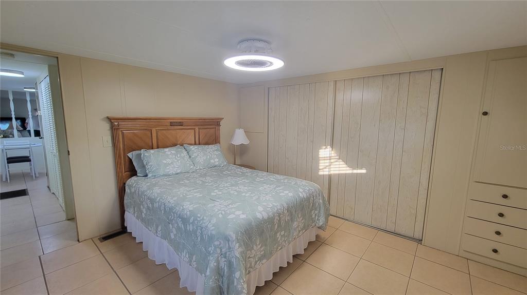 A bedroom features a bed with a patterned comforter, tiled floors, and built-in closet storage — 60 5TH STREET, PUNTA GORDA, FL