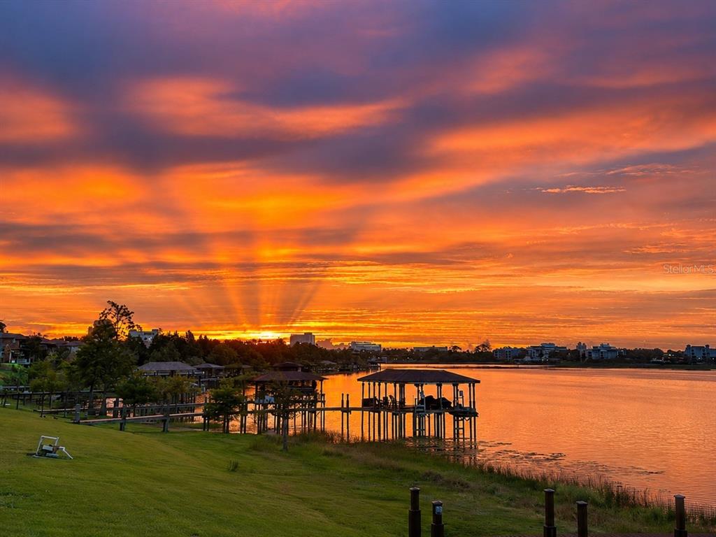 A vibrant sunset illuminates a lake with boat docks and a grassy shoreline — 10273 COVE LAKE DRIVE, ORLANDO, FL