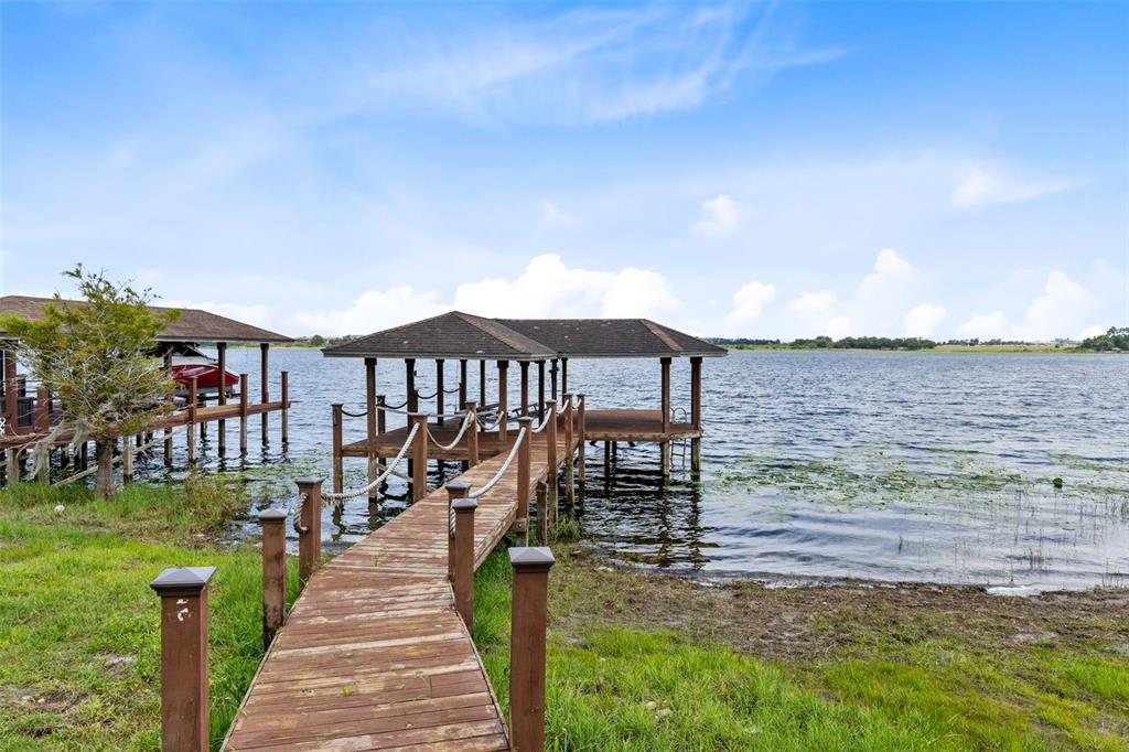 A wooden dock with a covered boat slip extends into a lake — 10273 COVE LAKE DRIVE, ORLANDO, FL