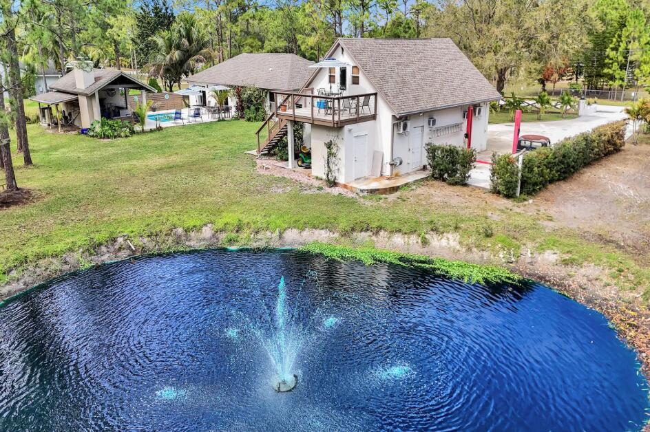 An aerial view shows a pond with a fountain in front of a two-story house — 14648 88th Place N, FL 33470, FL