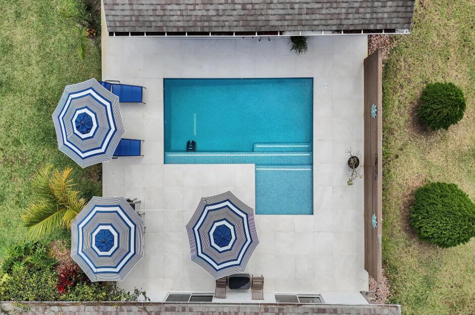 An aerial view shows a rectangular swimming pool with a tanning ledge on a patio — 14648 88th Place N, FL 33470, FL