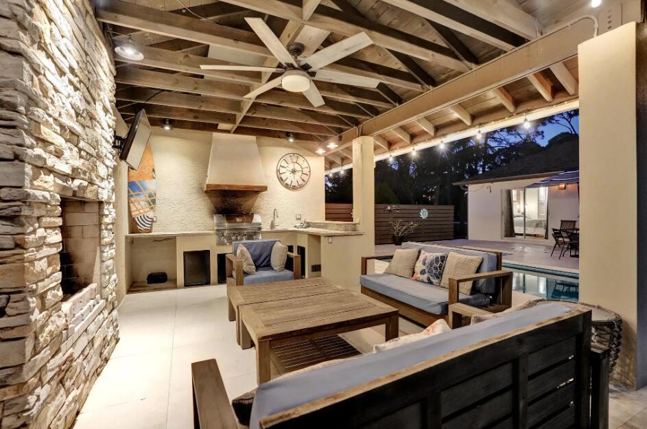 A covered outdoor patio features a stone fireplace, kitchen area, and comfortable lounge seating — 14648 88th Place N, FL 33470, FL