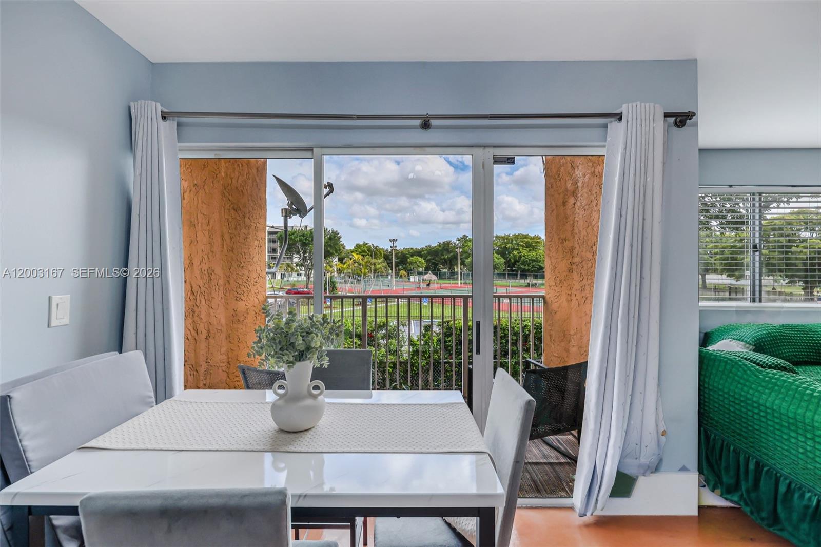 A dining area and living room with tile floors overlook a tennis court outside — 6255 Kendale Lakes Cir # 218, Miami FL 33183, MIAMI, FL
