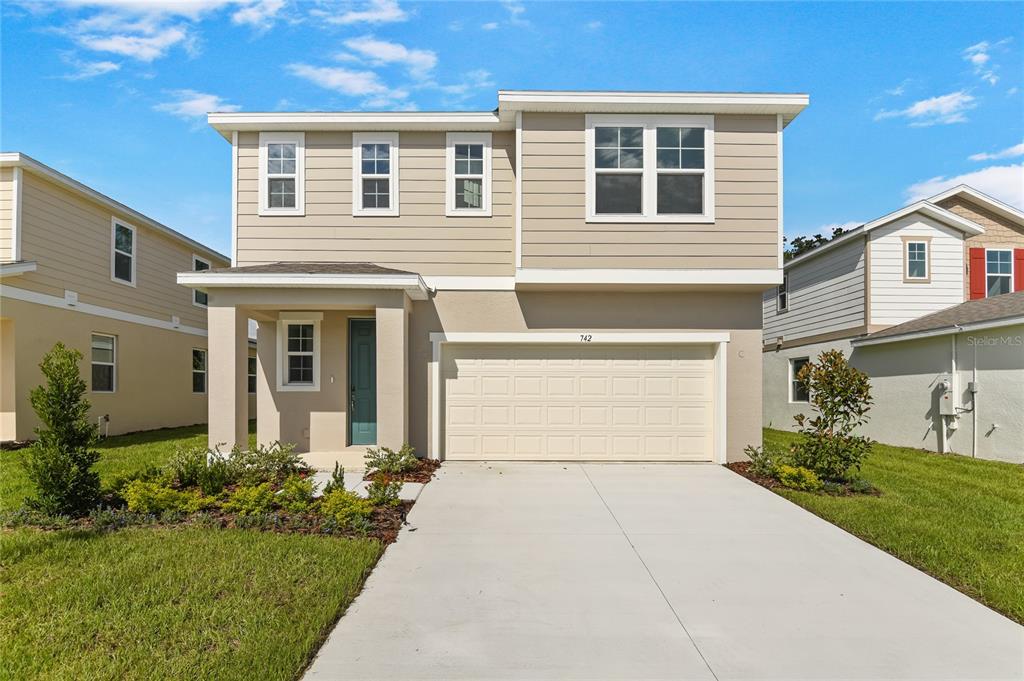 A two-story suburban house with beige siding, a two-car garage, and a concrete driveway — 742 LAKE DELL AVENUE, DUNDEE, FL