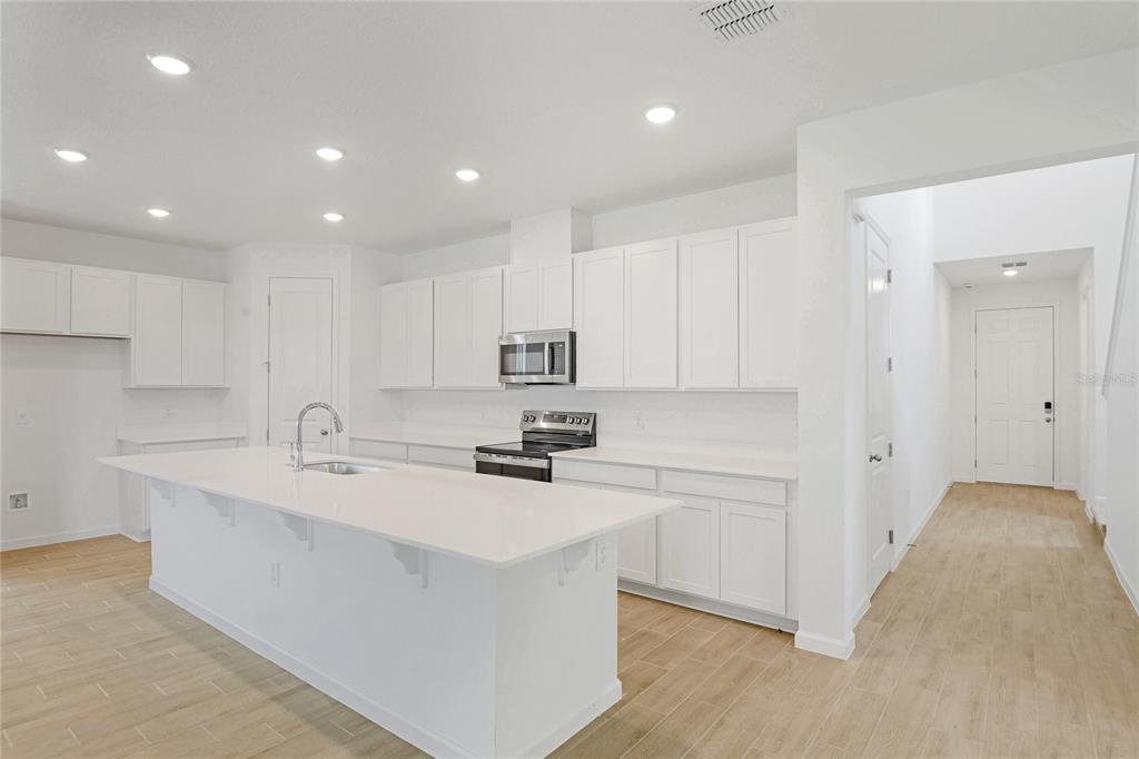 A modern kitchen features white cabinetry, a large island with a sink, and light flooring — 742 LAKE DELL AVENUE, DUNDEE, FL