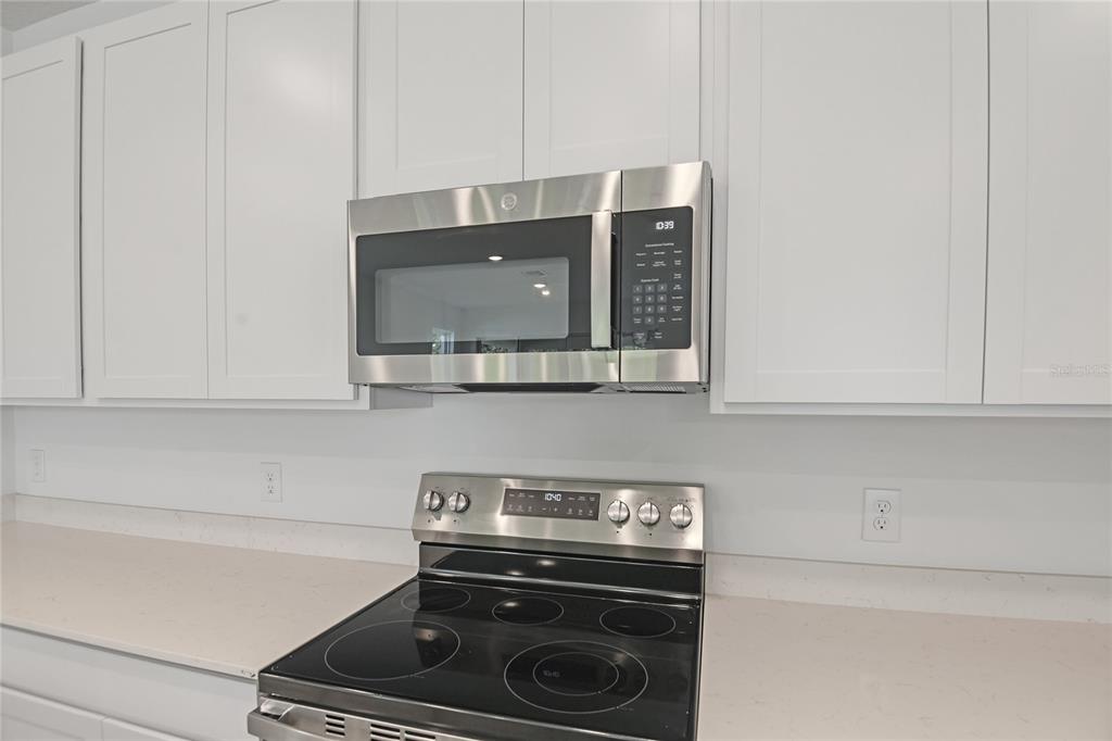 A stainless steel microwave is mounted above a glass-top electric range in a white kitchen — 742 LAKE DELL AVENUE, DUNDEE, FL