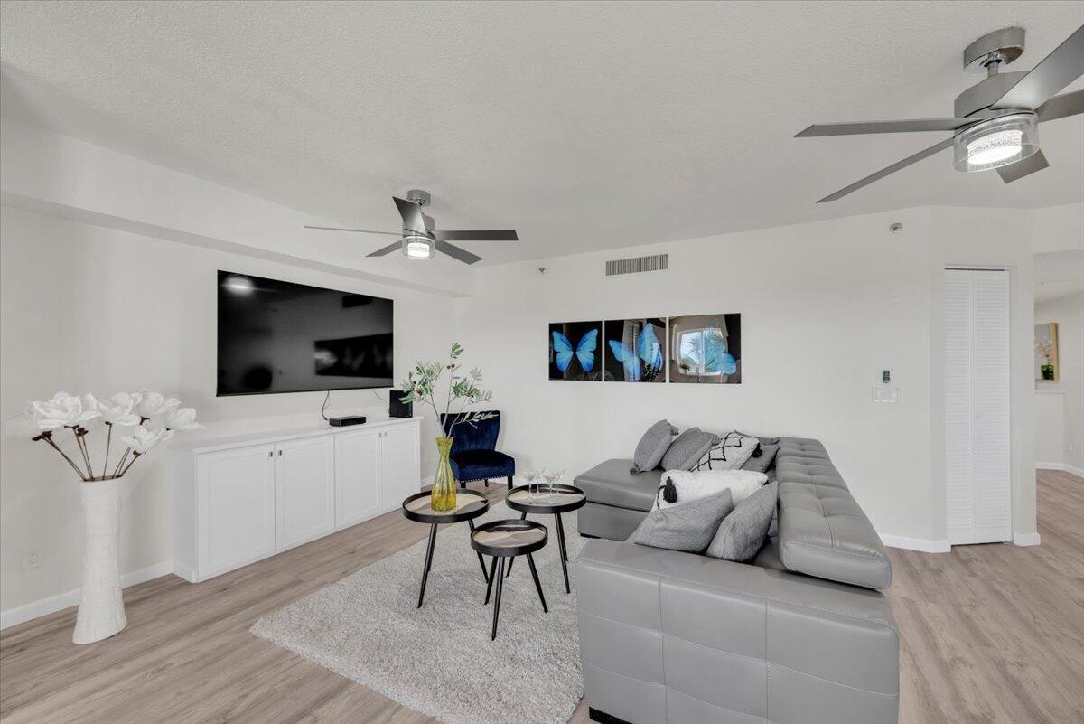 A living room features a grey sectional sofa, a television, and two ceiling fans — 275 Palm Avenue # B304, Jupiter FL 33477, JUPITER, FL