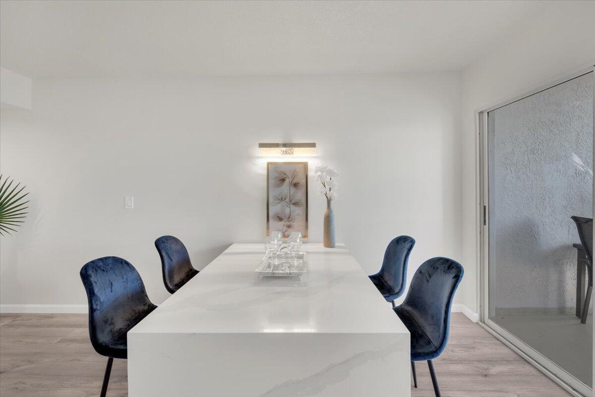 A dining room features a white marble table, four blue velvet chairs, and wall art — 275 Palm Avenue # B304, Jupiter FL 33477, JUPITER, FL