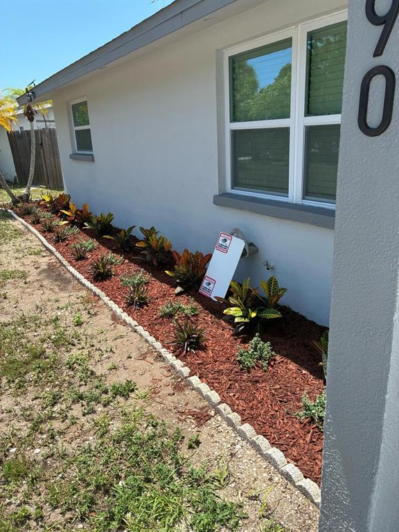 A side view of a house exterior featuring a landscaped garden bed with red mulch — 8290 OSPREY ROAD, ENGLEWOOD, FL