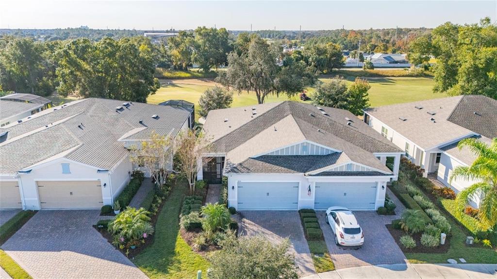 An aerial view shows three suburban houses with paved driveways and attached garages — 1855 FLORA PASS PLACE, KISSIMMEE, FL