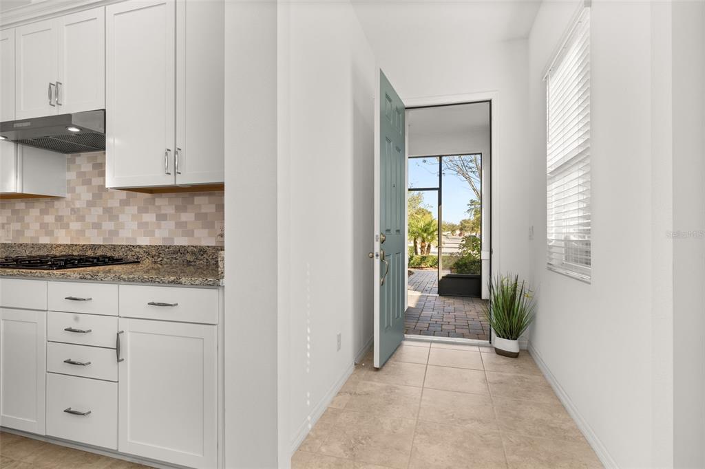 A kitchen with white cabinets and granite countertops opens to an exterior doorway and patio — 1855 FLORA PASS PLACE, KISSIMMEE, FL
