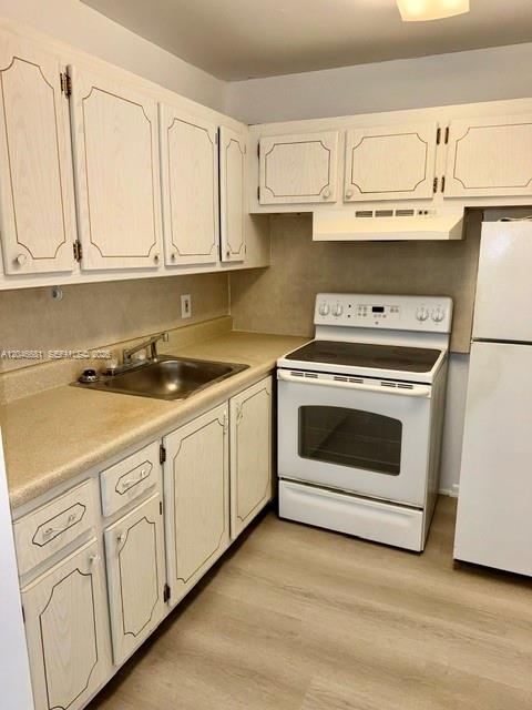 A kitchen with white cabinets, laminate countertops, a white stove, and light wood-look flooring — 41 Salisbury # B, West Palm Beach FL 33417, WEST PALM BEACH, FL