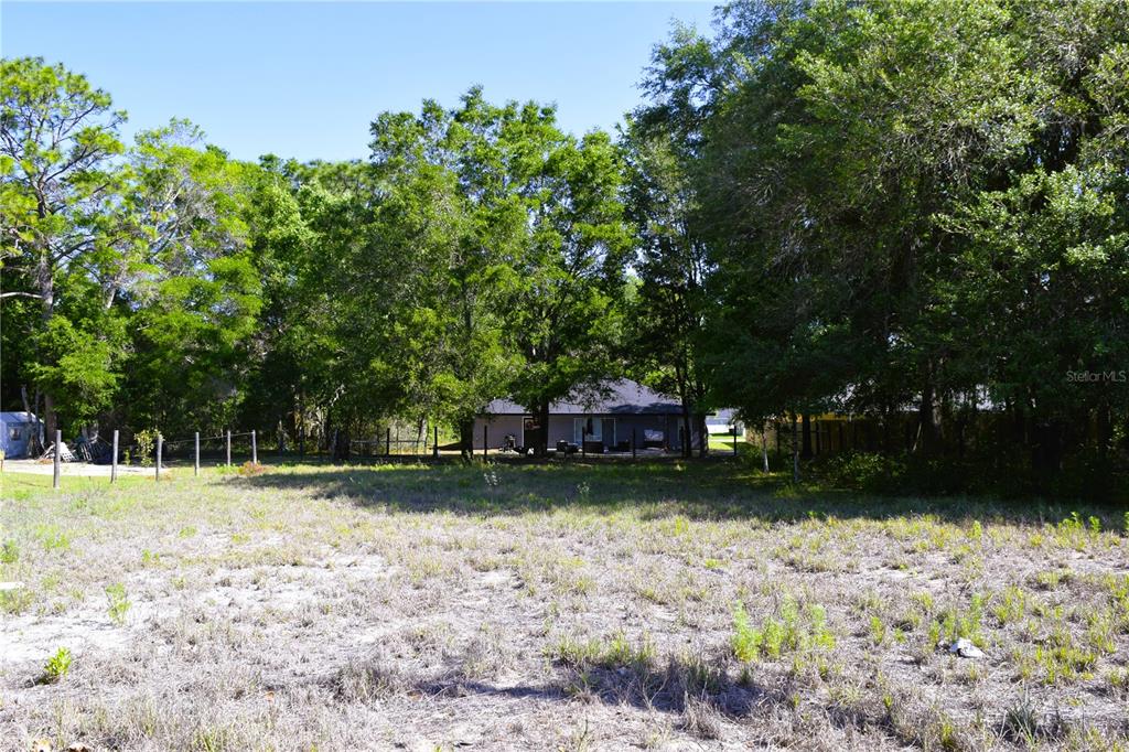 A view of a vacant, grassy lot with a house visible in the background — TBD SW 34 STREET, OCALA, FL