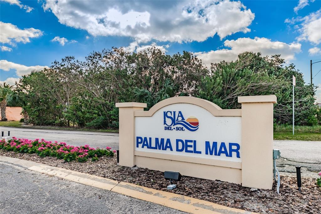 A beige monument sign for Isla Del Sol Palma Del Mar stands near a road — 6268 PALMA DEL MAR BOULEVARD S UNIT 102, ST PETERSBURG, FL
