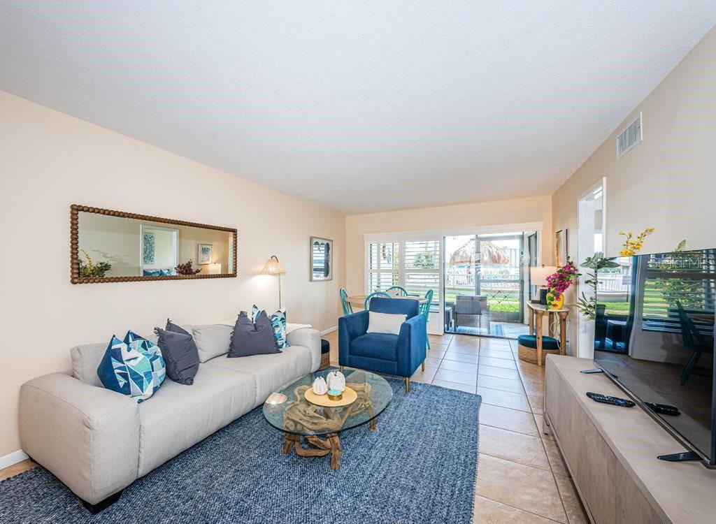 A living room features a blue rug, a light-colored sofa, a blue armchair, and tile flooring — 6268 PALMA DEL MAR BOULEVARD S UNIT 102, ST PETERSBURG, FL