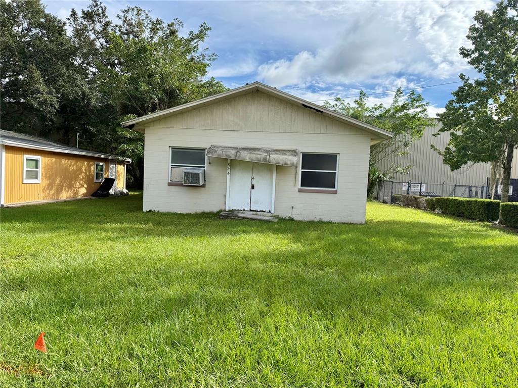 A small, light-colored, single-story house with a double-door entrance sits on a grassy lot — 844 KLONDIKE STREET, WINTER GARDEN, FL