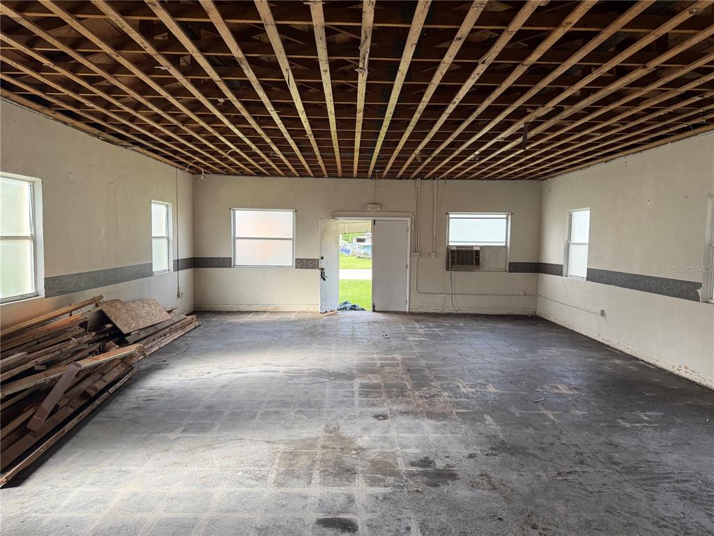 An unfinished room features an exposed wood ceiling, concrete flooring, and several windows — 844 KLONDIKE STREET, WINTER GARDEN, FL