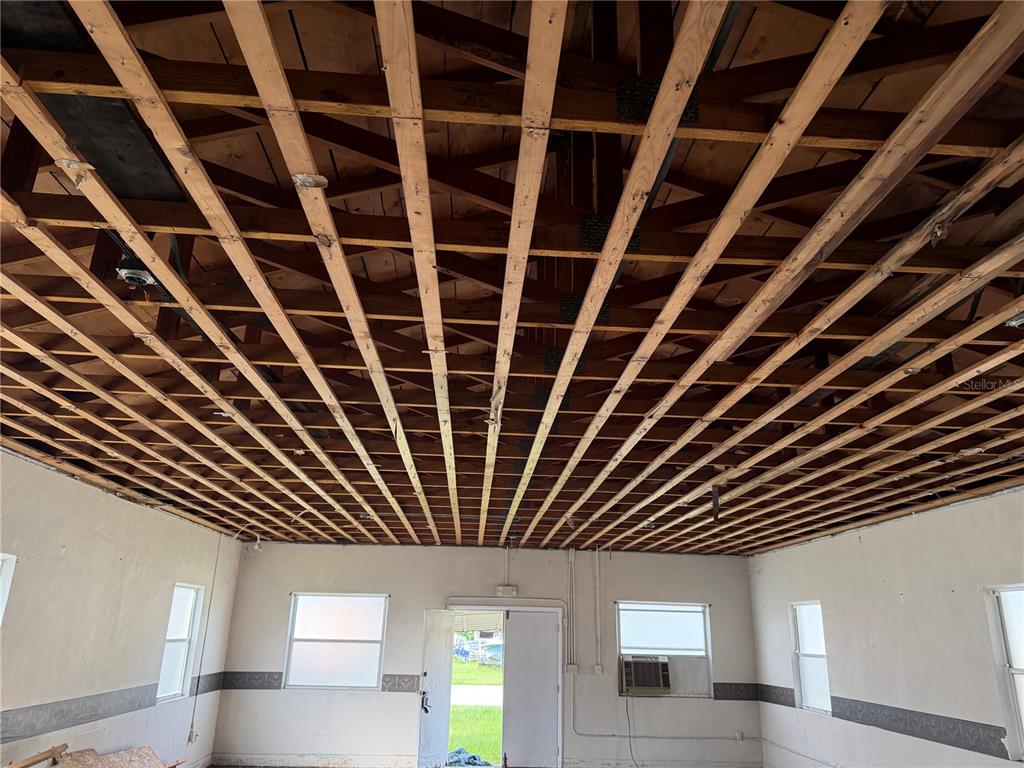 An interior room shows exposed wooden ceiling joists and unfinished walls with multiple windows — 844 KLONDIKE STREET, WINTER GARDEN, FL