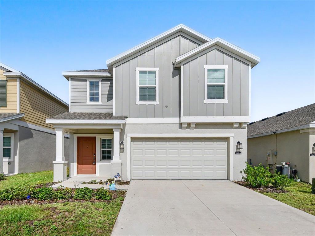 A two-story house with a gray vertical-siding upper level and a beige stucco lower level — 1906 NIAGRA DRIVE, DAVENPORT, FL
