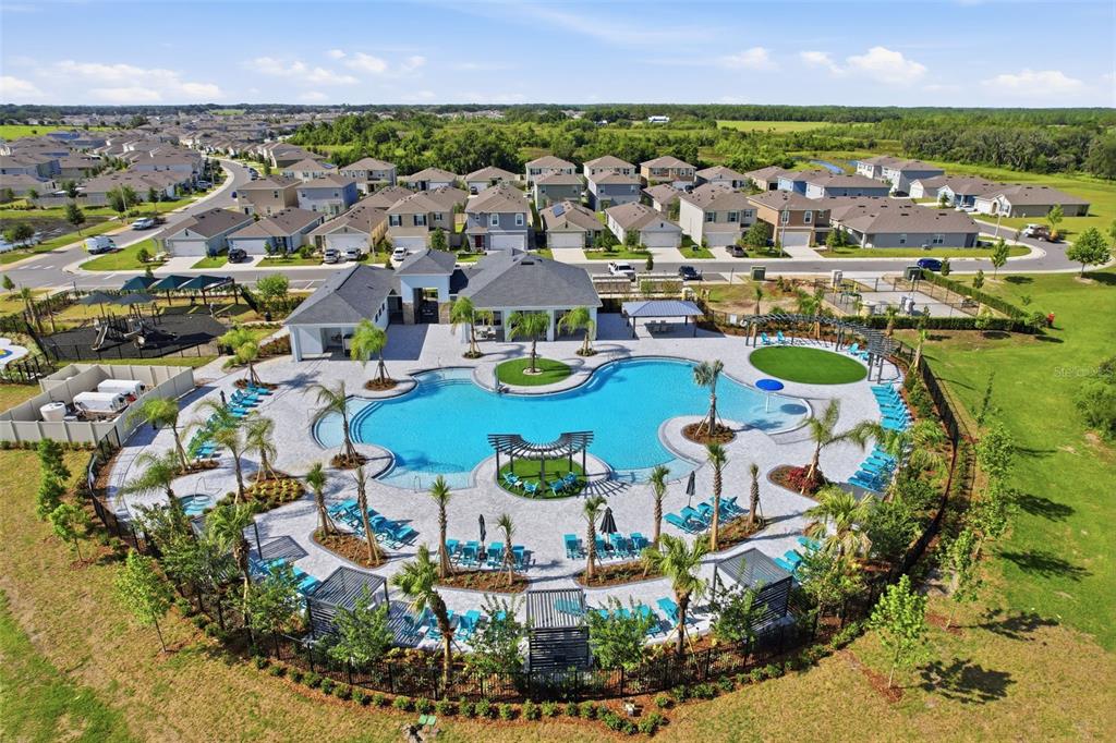 An aerial view shows a community swimming pool complex surrounded by residential houses and landscaping — 1906 NIAGRA DRIVE, DAVENPORT, FL