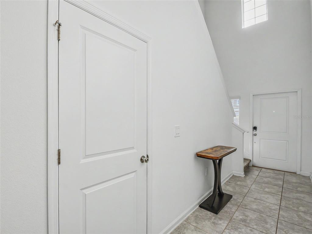 A white interior hallway features a tiled floor, a wooden console table, and two doors — 1906 NIAGRA DRIVE, DAVENPORT, FL