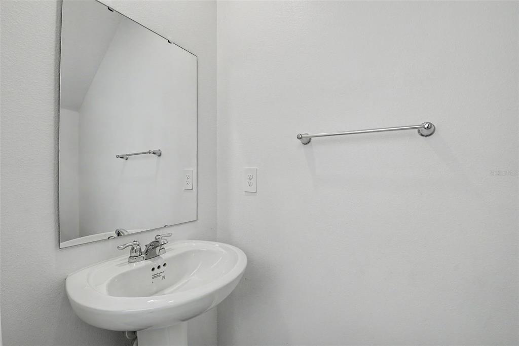 A bathroom features a pedestal sink, a wall-mounted mirror, and a chrome towel bar — 1906 NIAGRA DRIVE, DAVENPORT, FL