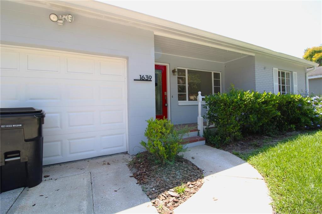 The exterior of a single-story house features a white garage door and a red door — 1639 OAKMONT LANE, ORLANDO, FL