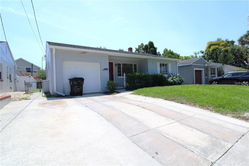 A light gray single-story house features a white garage door, a red front door, and a driveway — 1639 OAKMONT LANE, ORLANDO, FL