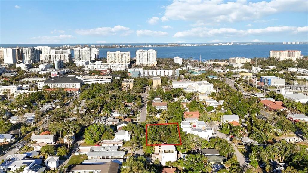 An aerial view shows a vacant, tree-covered lot outlined in red within a coastal city — 1721 8TH STREET, SARASOTA, FL