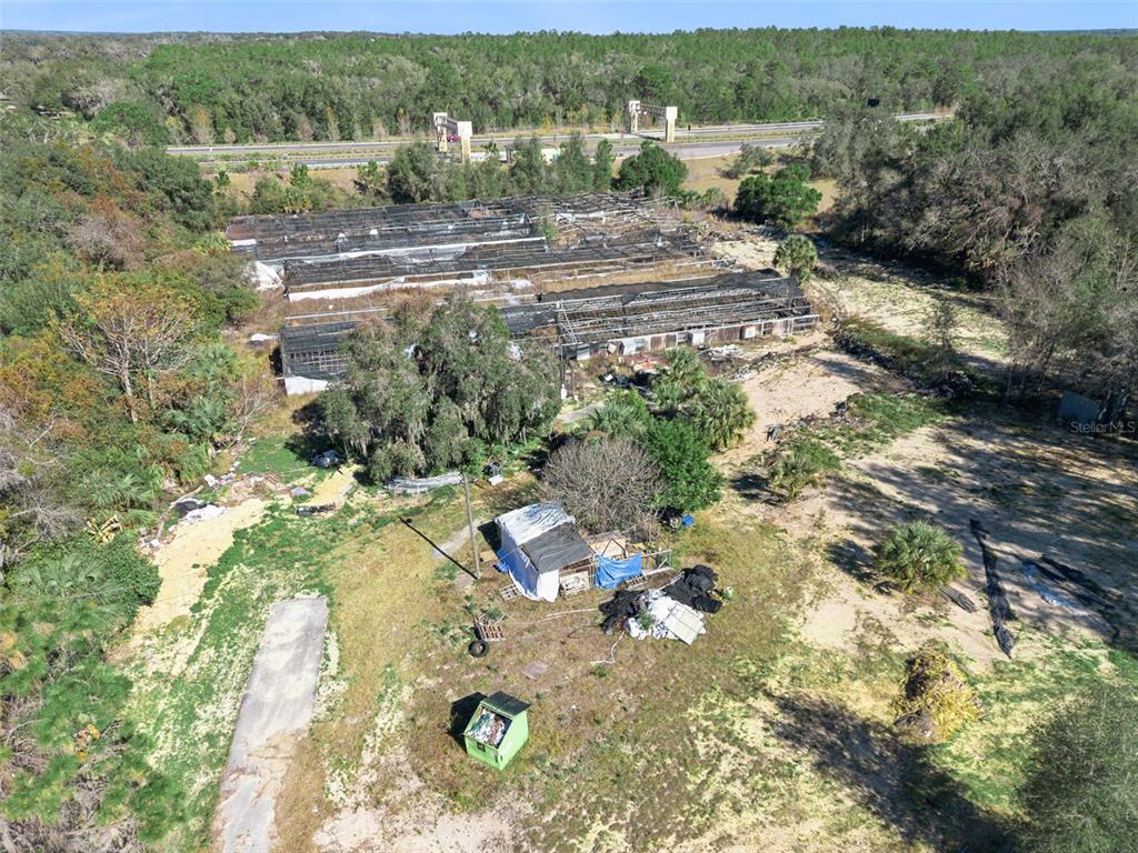 An aerial view shows a dilapidated greenhouse structure on a rural, wooded lot — 1909 HAAS ROAD, APOPKA, FL