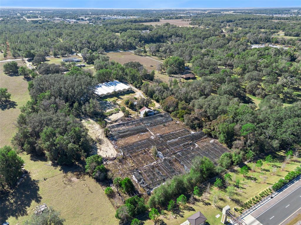 An aerial view shows a large property with a greenhouse structure and surrounding wooded land — 1909 HAAS ROAD, APOPKA, FL