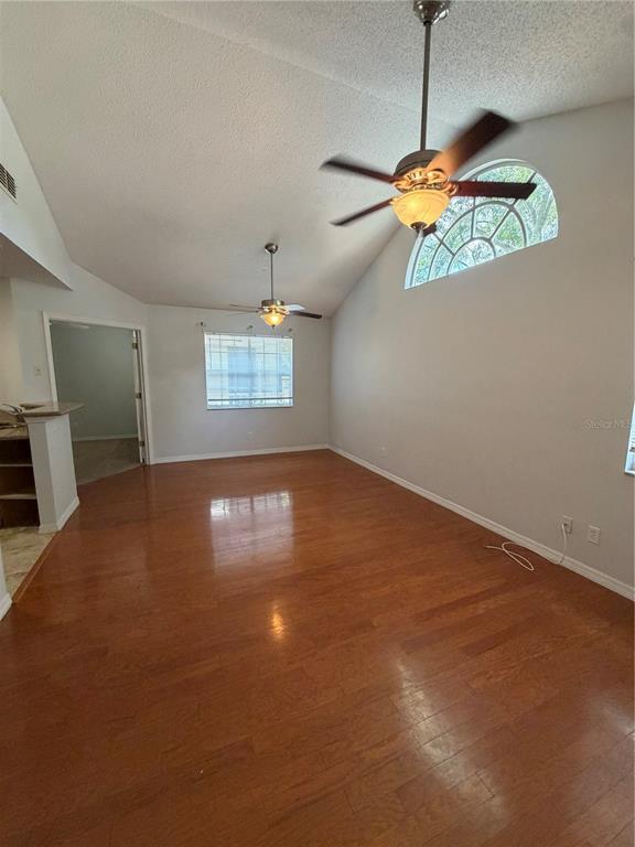 A living room features hardwood floors, vaulted ceilings, two ceiling fans, and an arched window — 949 BIRD BAY COURT UNIT 201, LAKE MARY, FL