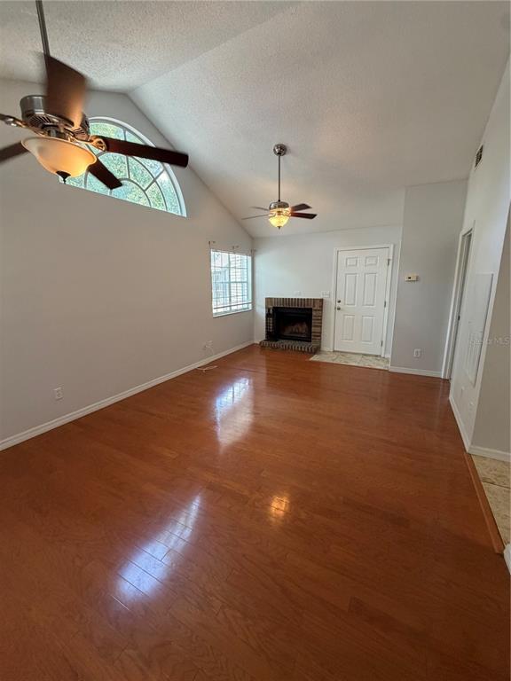 A living room with hardwood floors, a fireplace, two ceiling fans, and a vaulted ceiling — 949 BIRD BAY COURT UNIT 201, LAKE MARY, FL