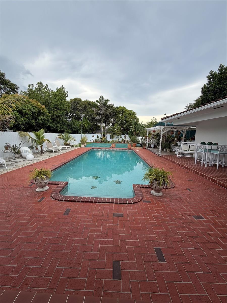 A rectangular swimming pool is surrounded by a red brick patio and lush landscaping — 3400 SW 108th Ave, Miami FL 33165, MIAMI, FL