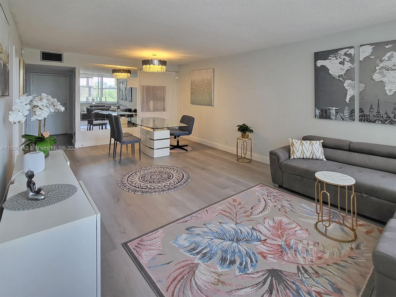A living and dining area features light wood flooring, a grey sofa, and mirrored walls — 1825 S Ocean Dr # 206, Hallandale Beach FL 33009, HALLANDALE BEACH, FL